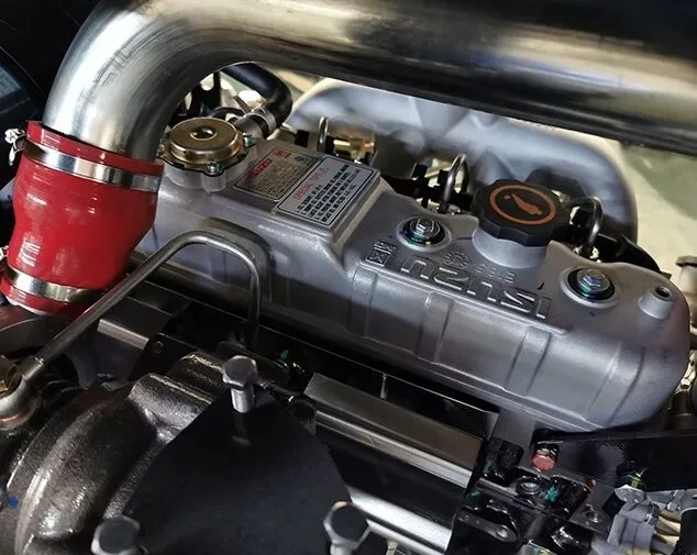 Close-up image of a car engine showing the cylinder head with labeled components, including a red rubber hose and engine parts